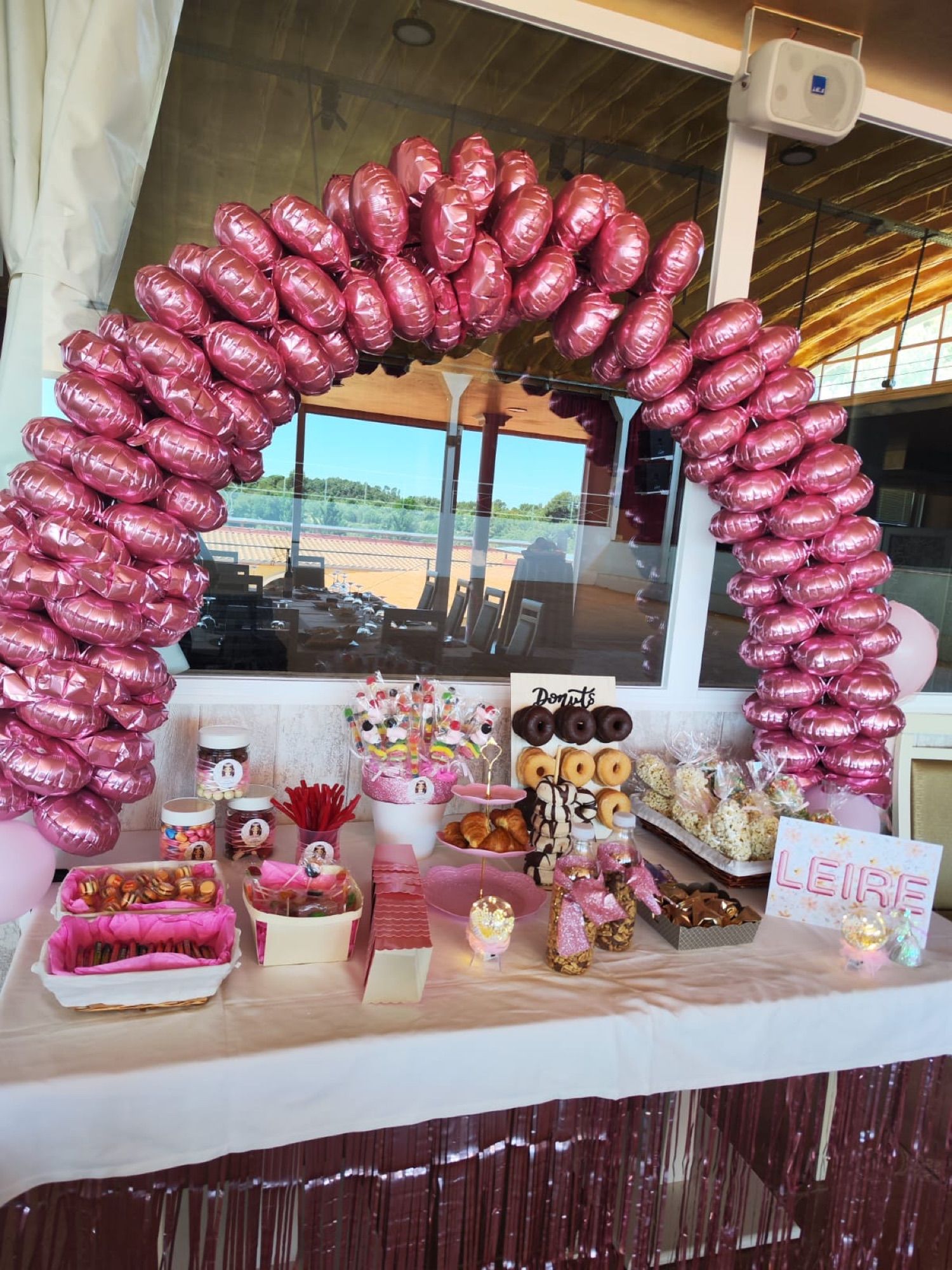 Arco de globos rosas y mesa dulce en una fiesta de cumpleaños