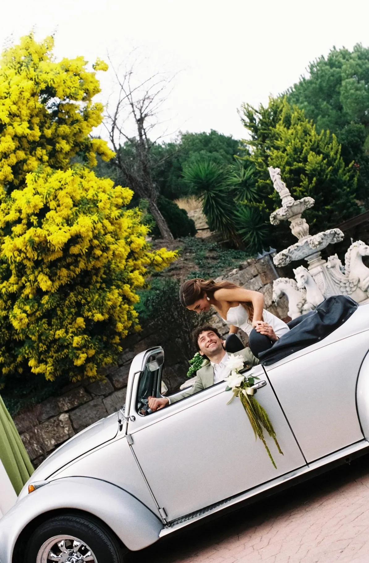 Novios en un descapotable clásico decorado con flores