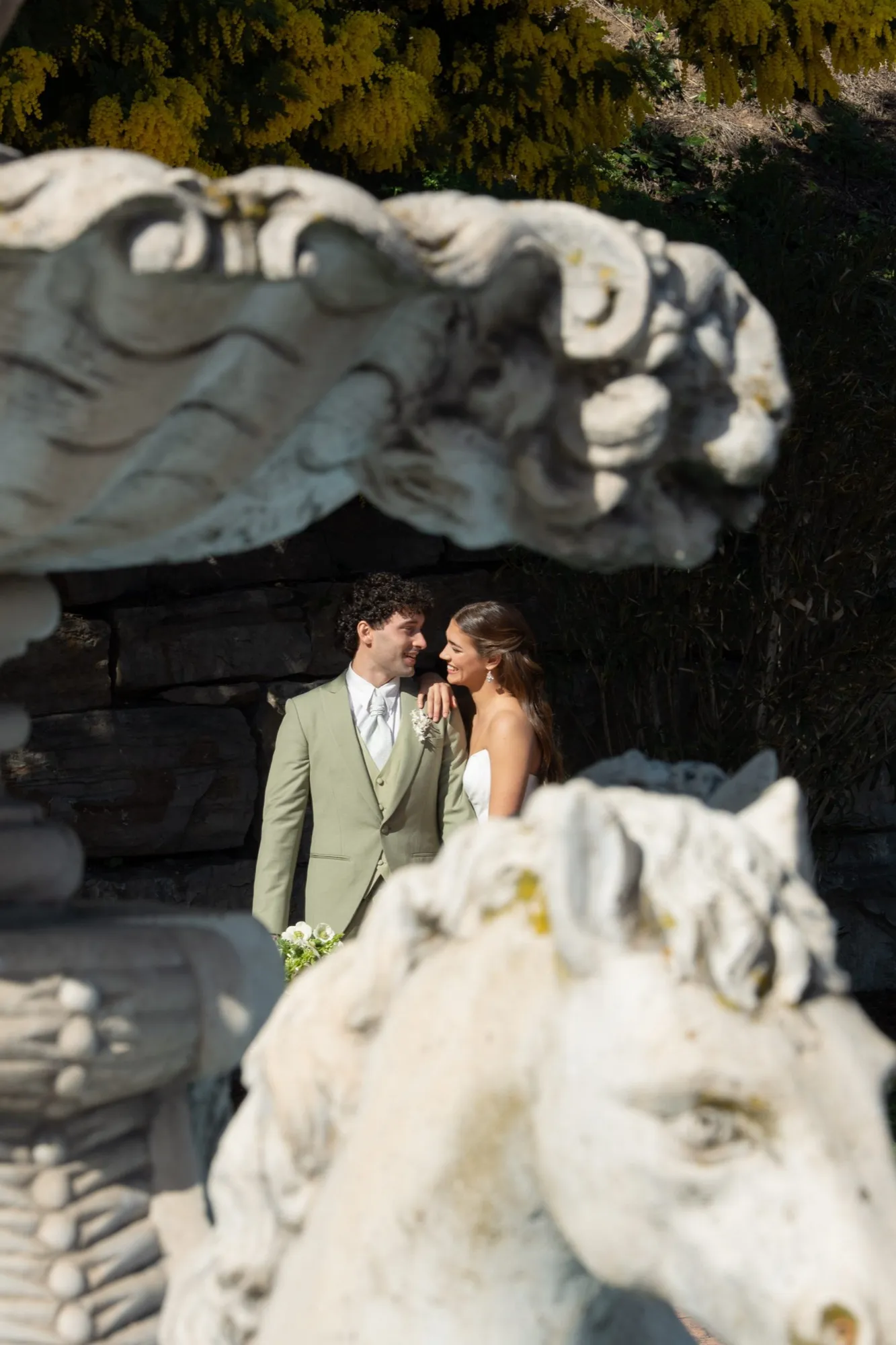 Novios junto a una escultura de caballo en piedra