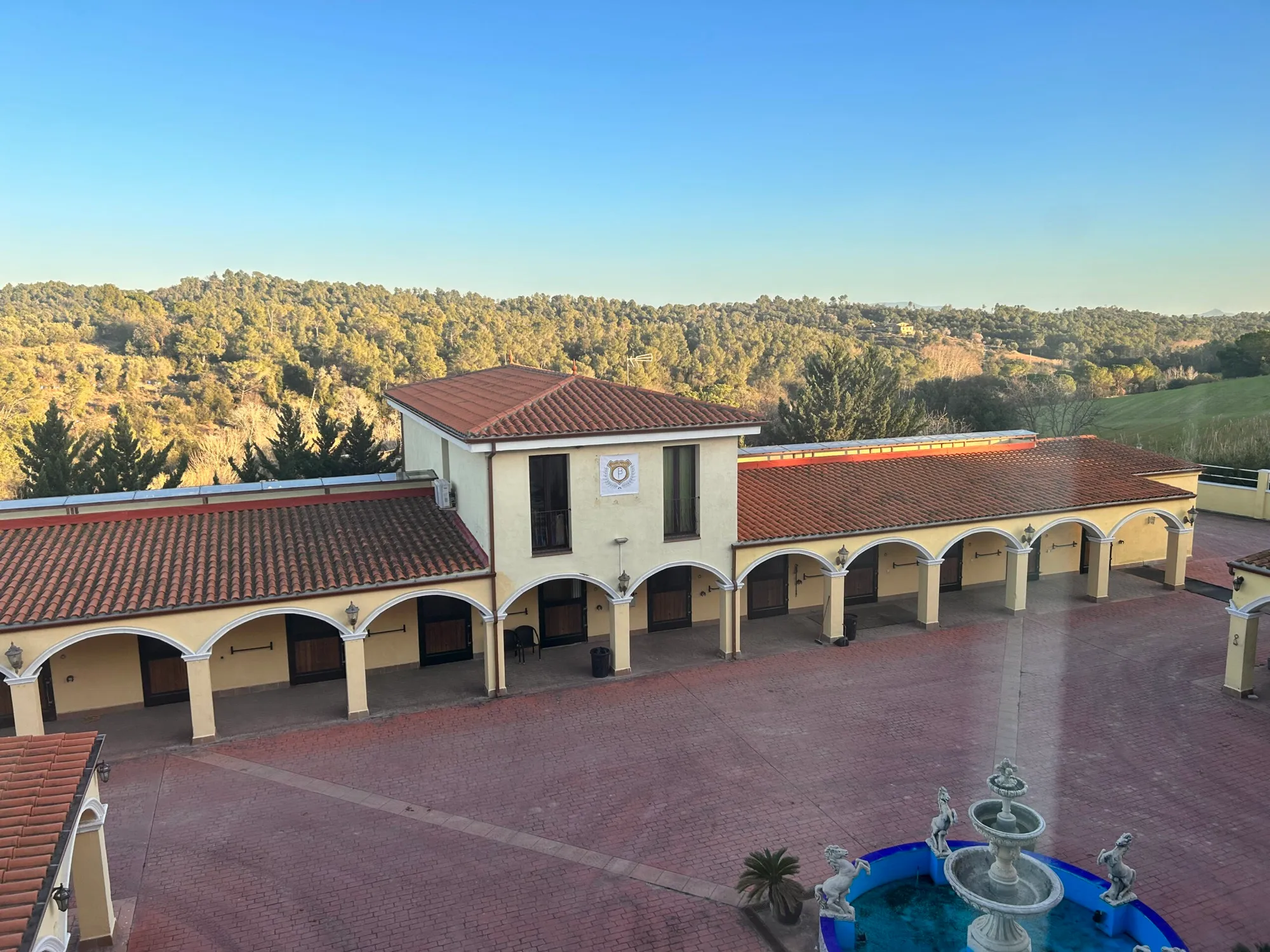 Vista de la finca con el patio y los pinares al atardecer